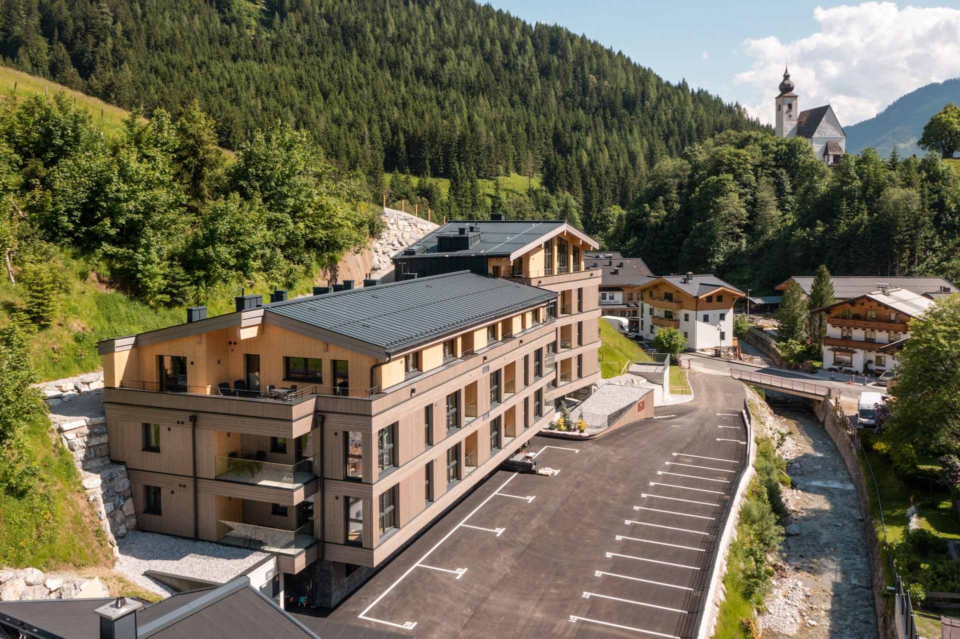 Wildbachlodge, Aussenansicht Sommer mit Kirche und Dorf