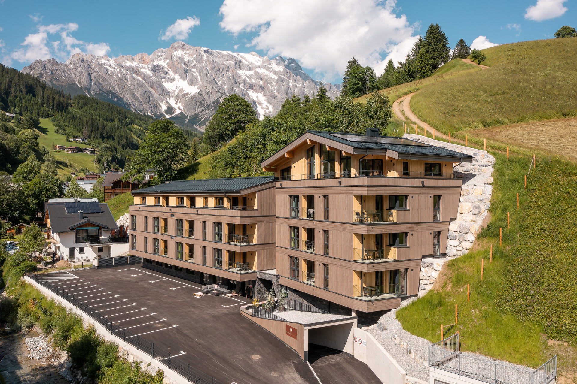 Wildbachlodge, Aussenansicht Sommer mit Blick zum Haupteingang und Parkplatz